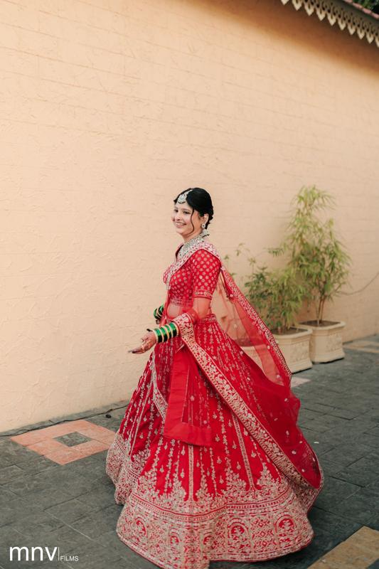 Bride in a red lehenga against a warm plaster wall