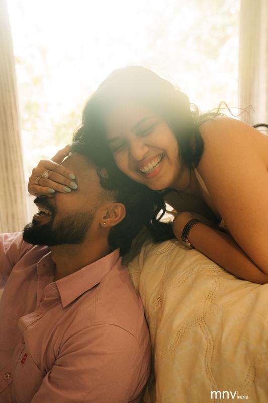 Couple laughing together, her arms around his shoulders